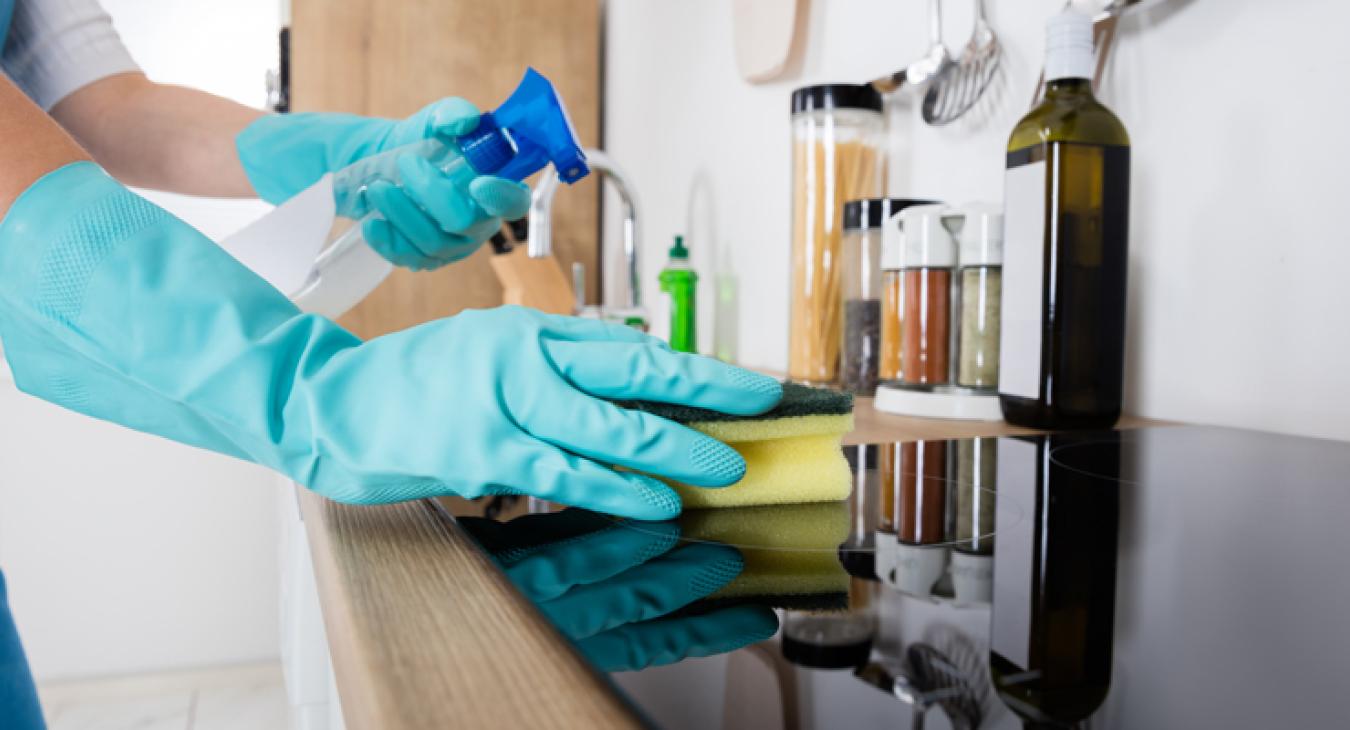 Domestic cleaner cleaning residential home kitchen Domestic cleaner cleaning kitchen worktop